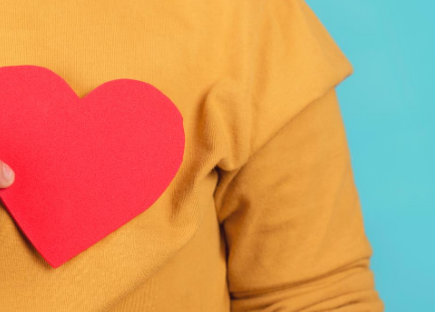 A person holding a paper cut-out heart