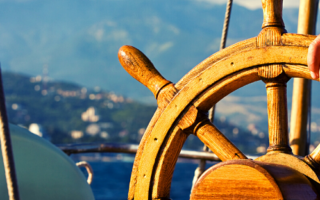 A hand on a steering wheel of a boat