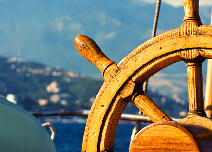 A hand on a steering wheel of a boat