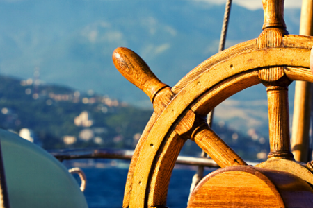 A hand on a steering wheel of a boat