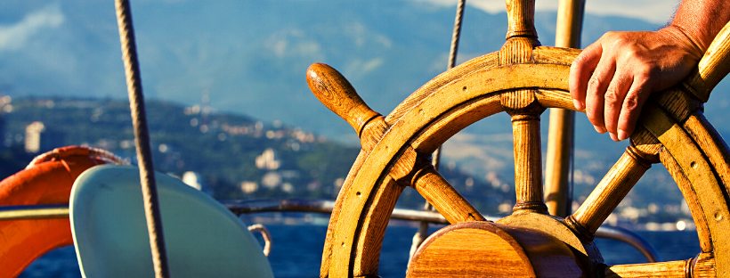 A hand on a steering wheel of a boat