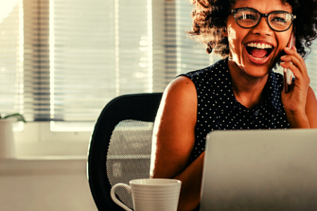 a woman sits at her desk and is happy