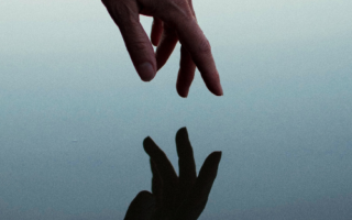 a hand reaches toward the water and is reflected
