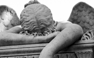 a statue of an angel with its forehead resting on its arm, dejectedly