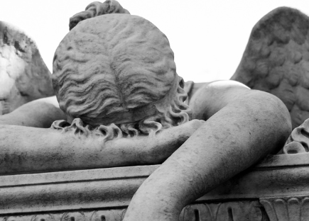 a statue of an angel with its forehead resting on its arm, dejectedly