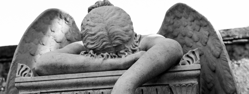 a statue of an angel with its forehead resting on its arm, dejectedly