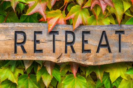 A wooden sign reading "retreat" with green foliage in the background