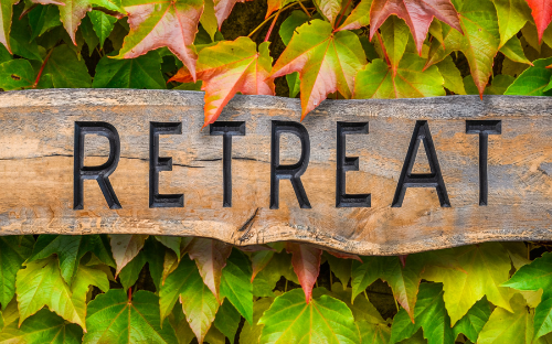 A wooden sign reading "retreat" with green foliage in the background